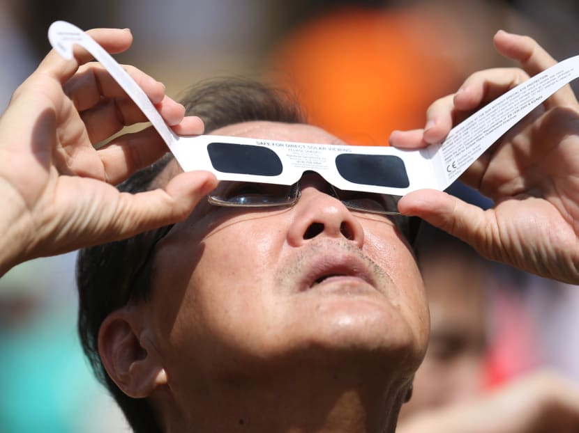 A man viewing the annual solar eclipse with protective glasses at Kebun Baru Spring Amphitheatre on Thursday (Dec 26) where more than 1,000 viewers gathered.