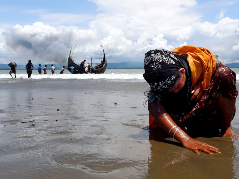 An exhausted Rohingya refugee woman touches the shore after crossing the Bangladesh-Myanmar border by boat through the Bay of Bengal, in Shah Porir Dwip, Bangladesh. Photo: Reuters