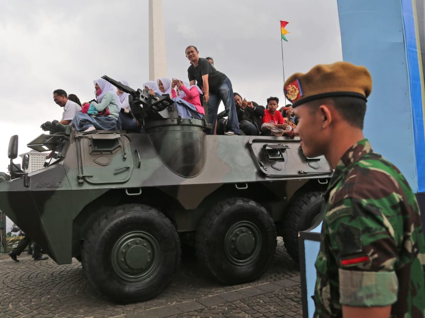 Indonesians ride on an Army armored vehicle during an exhibition in Jakarta, Indonesia, in 2014. AP file photo