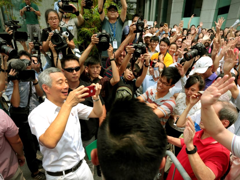 PM Lee Hsien Loong taking a photo of those who turned up at the PAP’s lunch-time rally at UOB Plaza yesterday where he reiterated to the crowd that his party has worked hard to improve lives. Photo: Jason Quah