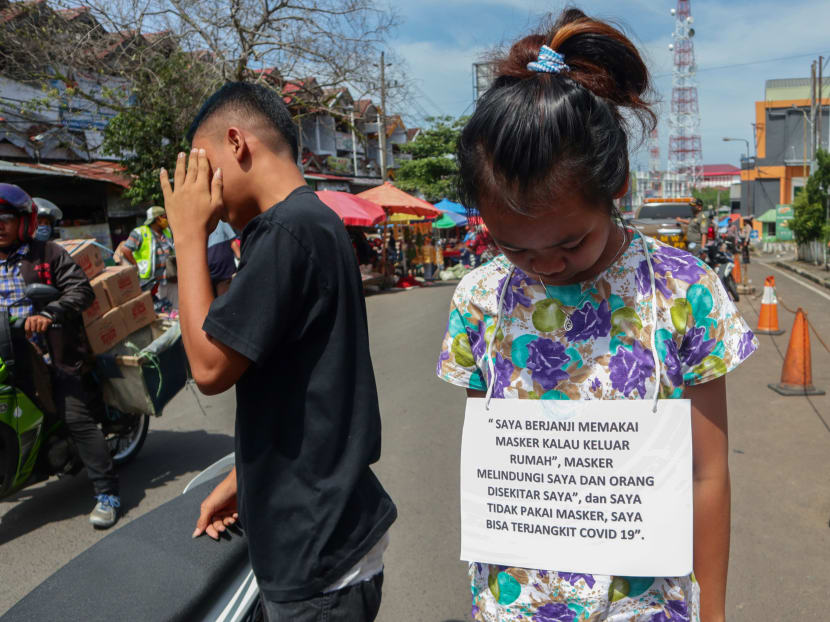 In this picture taken on May 13, 2020 a violator, wearing a paper necklace readings "I promise to wear face mask', which will be uploaded on social media, stands in a street during the Covid-19 coronavirus pandemic, in Bengkulu.