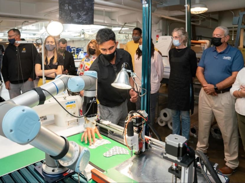 Siemens automation researcher Gokul Sathya Narayanan positions pieces of stiffened fabric for a Sewbo demonstration of robotic mask manufacturing at the Industrial Sewing and Innovation Center in Detroit, Michigan, United States on Aug 19, 2021. 