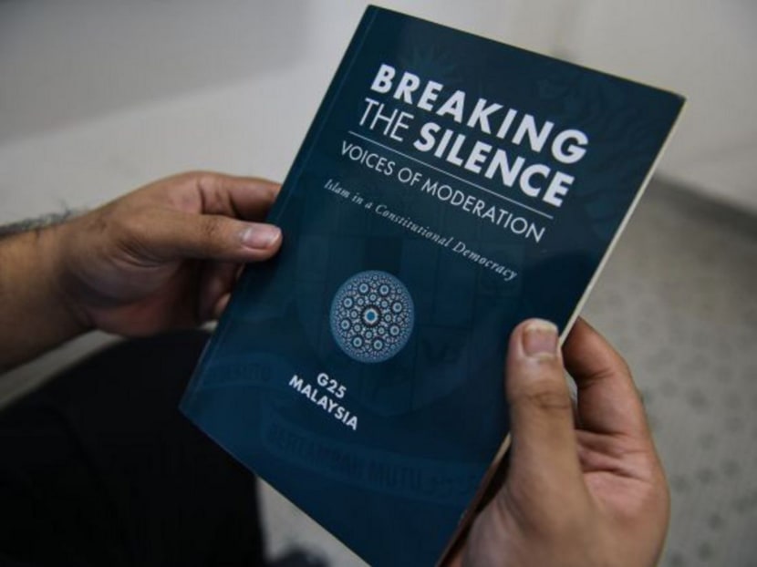 In this photo illustration taken in Kuala Lumpur on August 1, 2017, a man holds the book "Breaking The Silence: Voices Of Moderation - Islam In A Constitutional Democracy". Photo: AFP