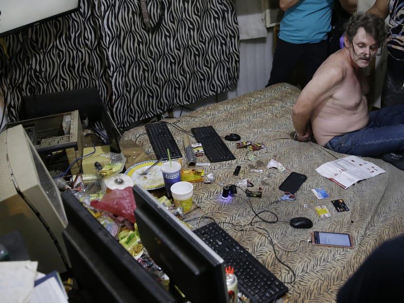 In this April 20, 2017, photo, suspected child webcam cybersex operator, David Timothy Deakin, from Peoria, Ill., with his hands tied behind his back during a raid by investigators, sits on his bed where he handles online sharing of videos of children engaging in sexual acts in Mabalacat, Philippines. Photo: AP