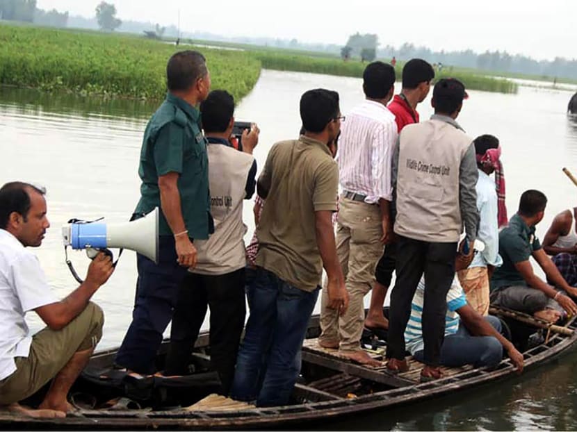 Bangladesh wildlife officials look on from a boat as they observe a wild elephant in a watercourse at Sarishabari in Jamalpur District some 150kms north of Dhaka. Photo: AFP