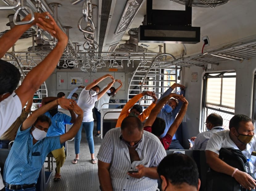 Commuters take part in a yoga session inside a train coach in Mumbai on June 21, 2021, to mark International Yoga Day.