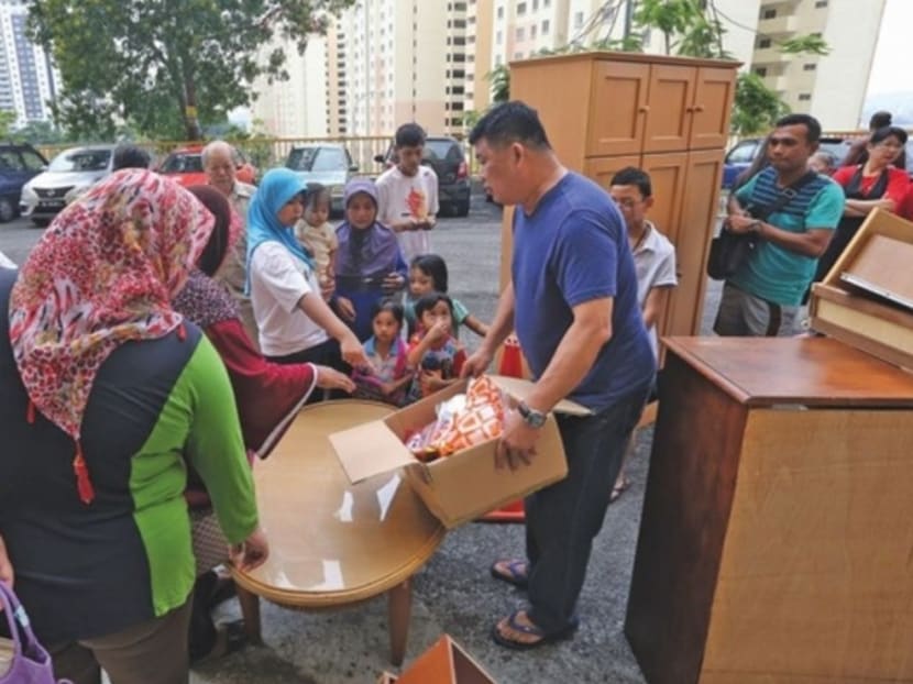 Iswadi (right) looks on in appreciation as Kuan presents items for his family, which lost everything in the fire recently. Photo: Malay Mail Online