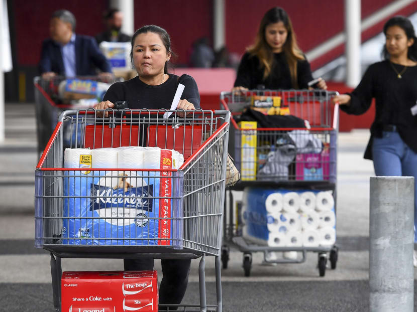 People leave a Costco warehouse in Melbourne with rolls of toilet paper among their groceries on March 5, 2020.