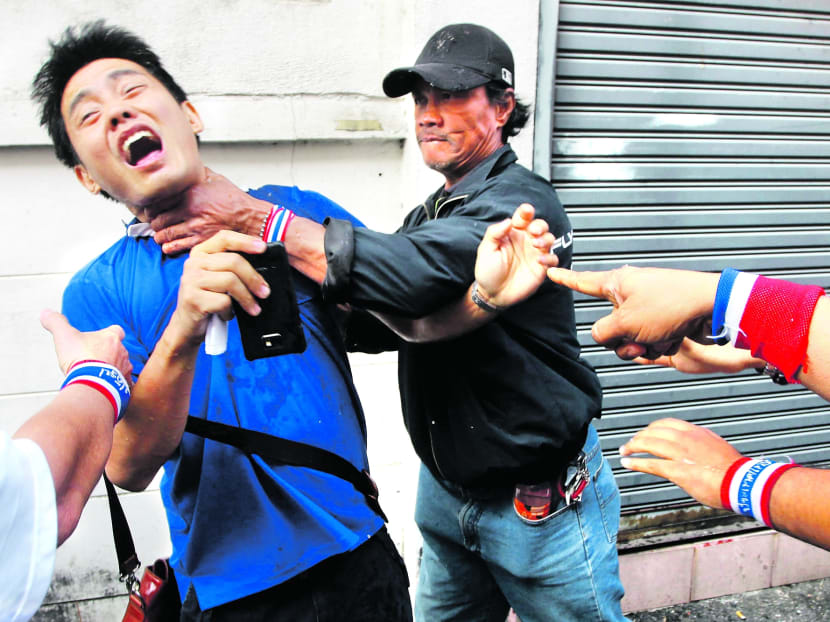 Anti-government protesters attacking a voter near a polling station in Bangkok 
yesterday as hundreds of thousands of people were prevented from voting. PHOTO: Reuters