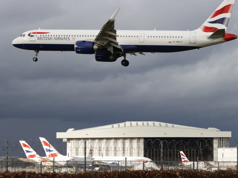 A British Airways aircraft flies over parked British Airways planes on the tarmac at London Heathrow Airport in west London on February 5, 2021.