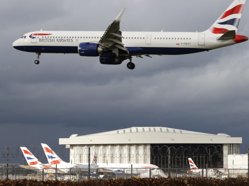 A British Airways aircraft flies over parked British Airways planes on the tarmac at London Heathrow Airport in west London on February 5, 2021. A British Airways aircraft flies over parked British Airways planes on the tarmac at London Heathrow Airport in west London on February 5, 2021.