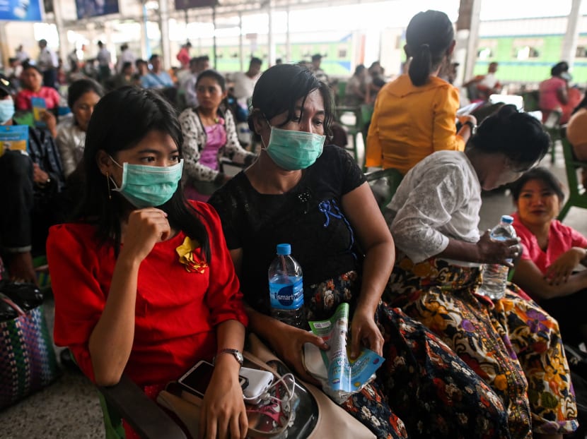 People wear face masks while waiting for a ride at the central railway station in Yangon on March 19, 2020.