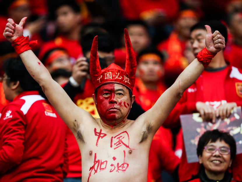 A fan gestures inside Helong Stadium ahead of a 2018 FIFA World Cup qualifier match between China and South Korea in Changsha, Hunan province, China, March 23, 2017. The Chinese characters written on his hat read "China wins." Photo: Reuters