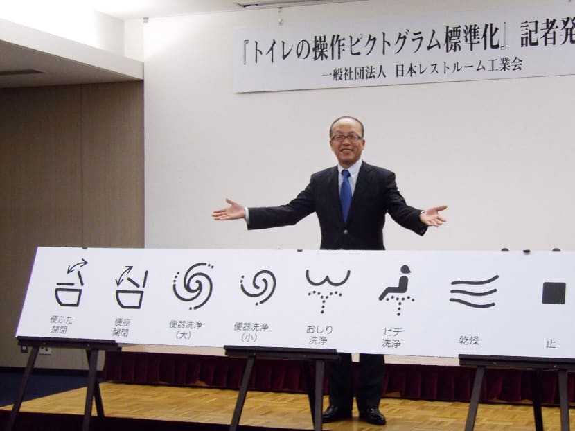 This picture taken on January 17, 2017 shows Madoka Kitamura, chairman of the Japan Sanitary Equipment Industry Association, showing off unified signs for high-tech toilet functions in Tokyo. Photo: AFP