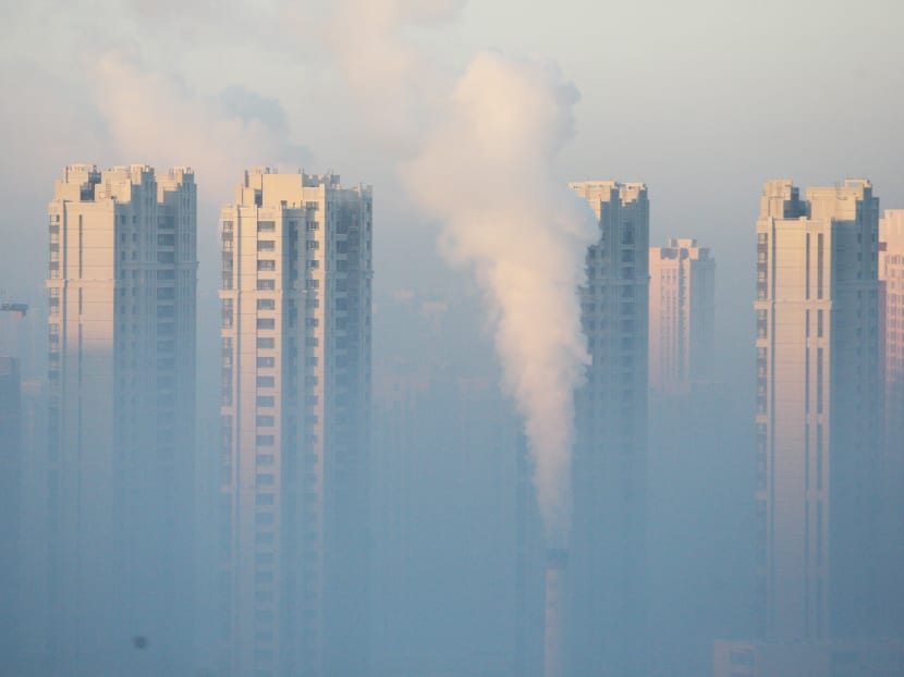 A chimney is seen in front of residential buildings during a polluted day in Harbin, Heilongjiang Province, China, January 21, 2016. Photo: Reuters