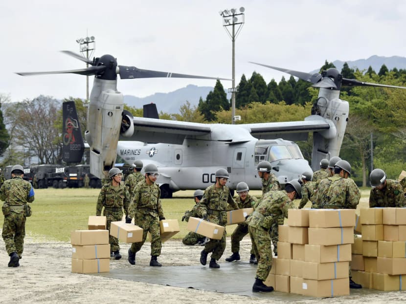 Japan Ground Self-Defense Force soldiers carry aid materials from a U.S. military Osprey aircraft (behind them) after a series of earthquakes, at Hakusui sports park in Minamiaso town, Kumamoto prefecture, southern Japan, in this photo taken by Kyodo April 18, 2016. Photo: REUTERS/KYODO
