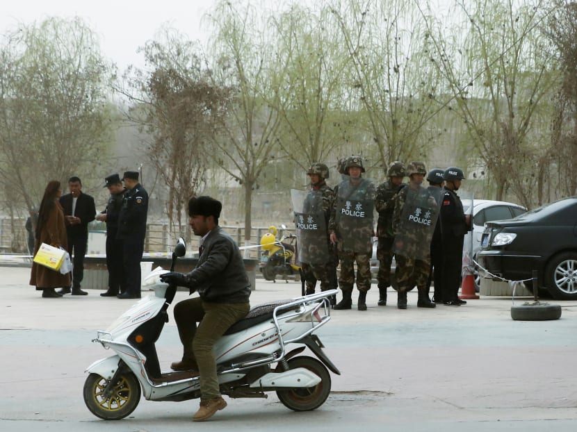 Police officers check the identity cards of a people as security forces keep watch in a street in Kashgar, Xinjiang Uighur Autonomous Region, China on March 24, 2017.