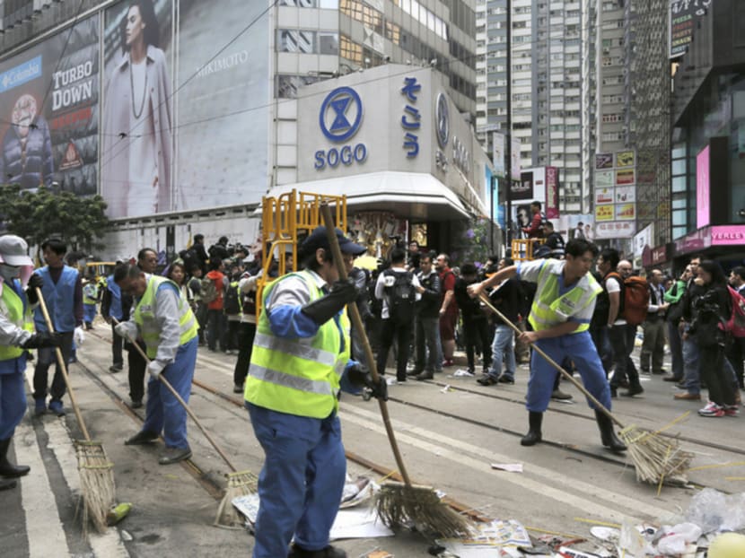 Workers cleaning up after the police cleared barricades and tents on a main road in Causeway Bay, Hong Kong, yesterday. Photo: AP