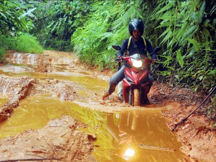 Teacher Ahmad Saidin Mohd Idris tackles tough road conditions on his way to and from school. Photo: New Straits Times