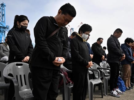 Guests bow their heads in silence during a remembrance ceremony for families of victims in front of the salvaged Sewol ferry at a port in Mokpo, South Jeolla Province, on April 16, 2024, as South Korea marked the 10th anniversary of the country's worst-ever maritime disaster, when hundreds of schoolchildren died after the overloaded Sewol ferry capsized and sank.