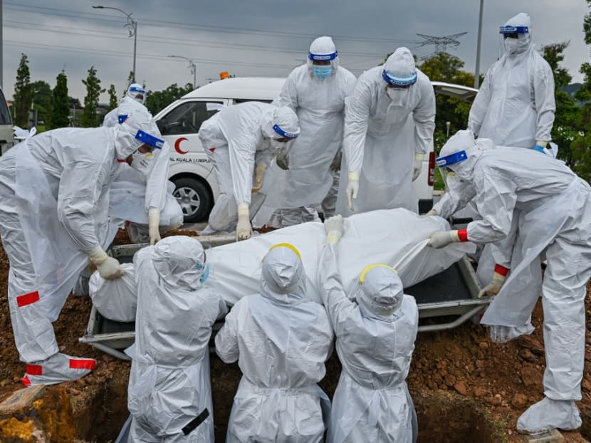 Volunteers wearing protective suits lay down the body of a Covid-19 coronavirus victim for burial at the Raudhatul Sakinah Muslim cemetery in Kuala Lumpur on June 15, 2021.