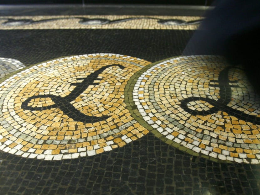 An employee is seen walking over a mosaic of pound sterling symbols set in the floor of the front hall of the Bank of England in London, in this March 25, 2008 file photograph. Photo: Reuters