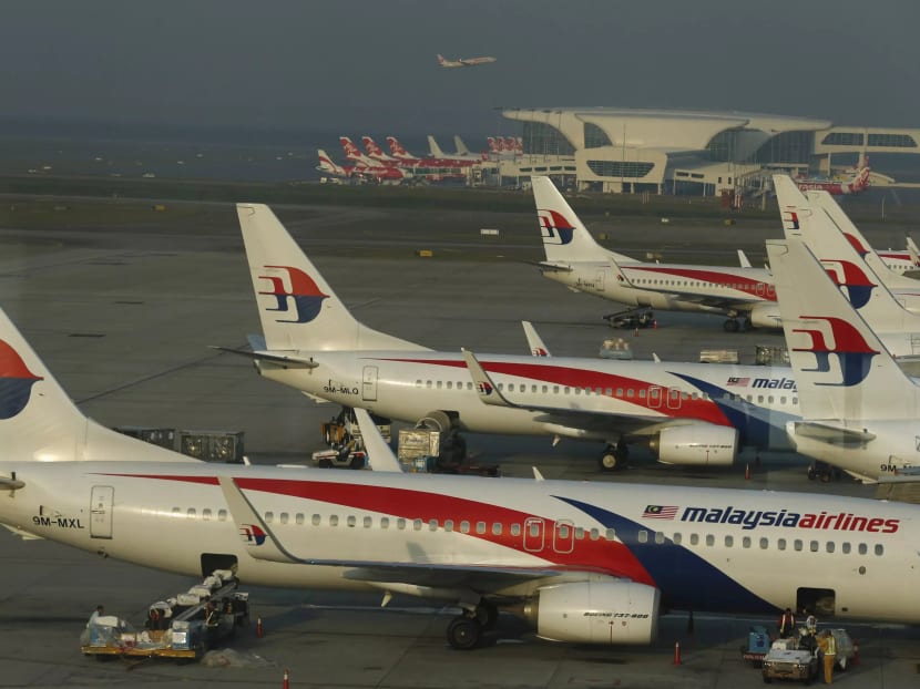 Ground crew work among Malaysia Airlines planes on the runway at Kuala Lumpur International Airport in Sepang.