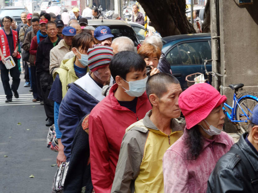 This photo taken on February 26, 2014 shows local homeless people lining up for free food outside the Grace Home Church in Taipei. In recent years the gap in Taiwan between the rich and poor has widened rapidly, reaching a record level in 2011 as the wealthiest families earned 96 times more than the poorest. Photo: AFP