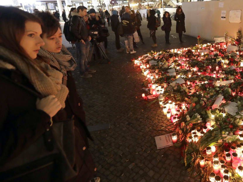 Two women stay in front of candles close to a Christmas market beside the memorial church in Berlin, Germany, Wednesday, Dec. 21, 2016, two days after a truck ran into a crowded Christmas market and killed several people. Photo: AP