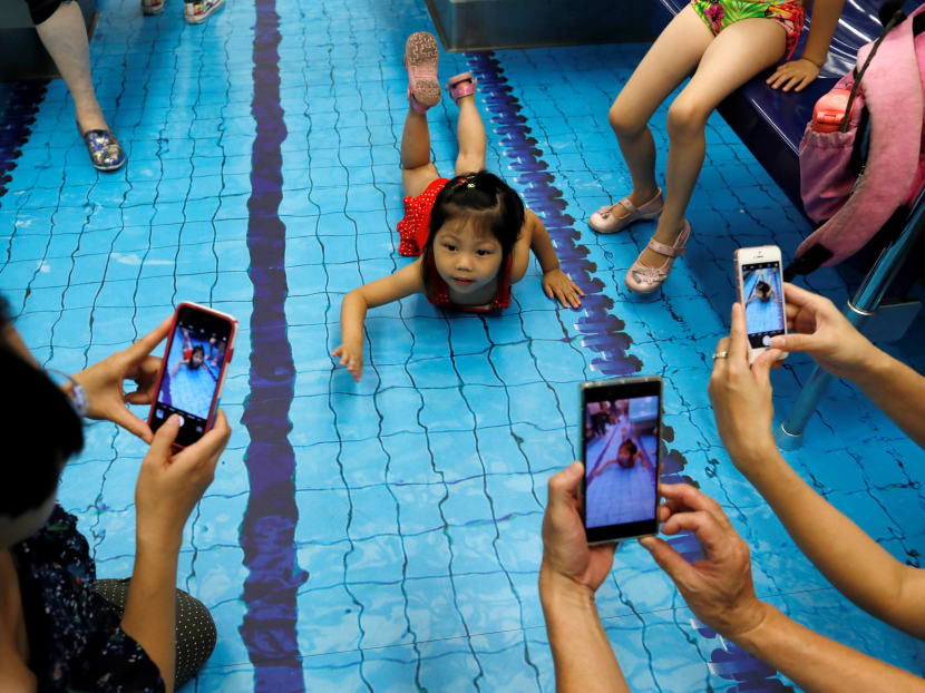 People take photos as a child poses in a sports-themed Mass Rapid Transit (MRT) train in Taipei, Taiwan, which has been decorated to look like a swimming pool. The trains were decorated to commemorate the Summer Universiade 2017. Photo: Reuters