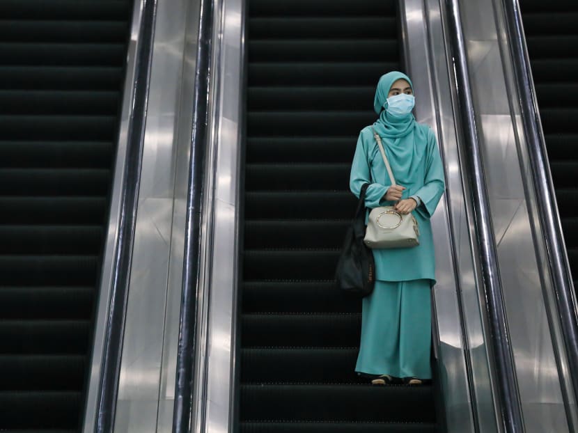 A woman wears a protective mask as she rides an escalator in Kuala Lumpur, Malaysia, on Feb 10, 2020.