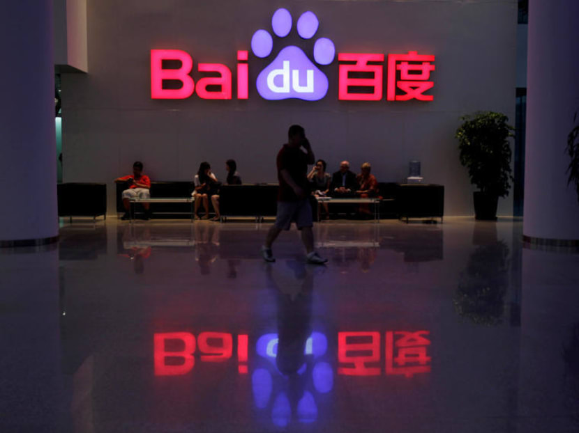 A employee uses his mobile phone as he walks past the company logo of Baidu at its headquarters in Beijing, August 5, 2010. Photo: Reuters