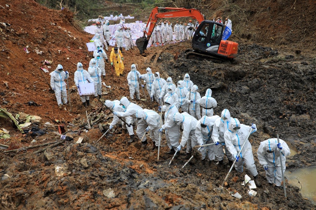 This photo taken on March 26, 2022 shows paramilitary police officers combing through the site of where China Eastern flight MU5375 crashd, in Tengxian county, Wuzhou city, in China's southern Guangxi region. 