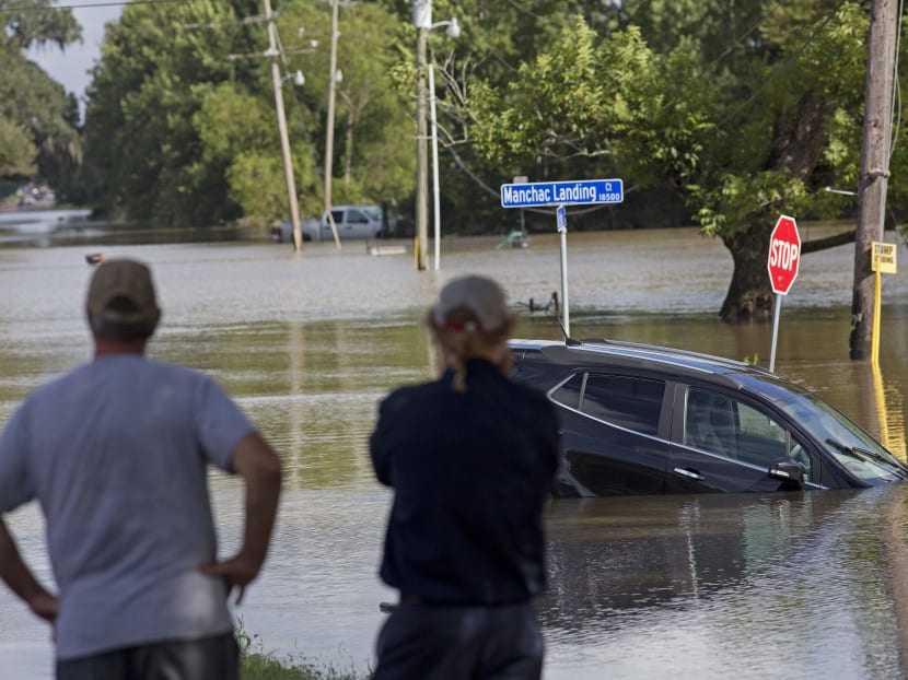 Residents survey the flood water on Old Jefferson Highway at Bayou Manchac in Prairieville, La., Aug 16. Photo: AP