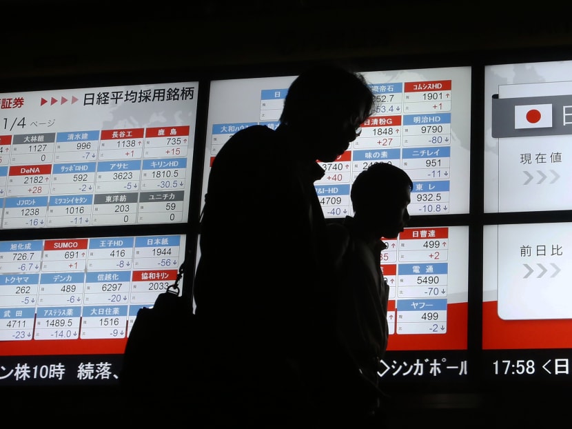People walk past an electronic stock indicator of a securities firm in Tokyo. Photo: AP
