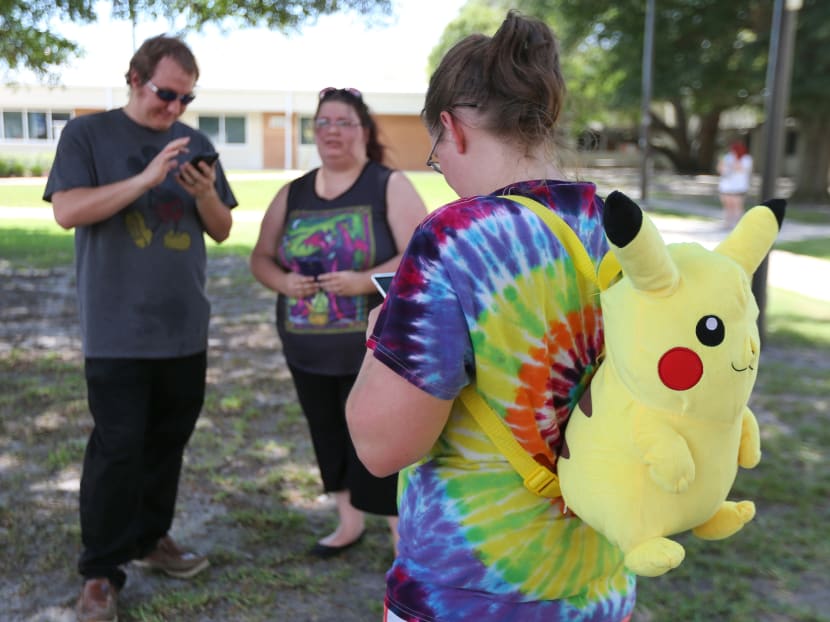 Victoria Baker, right, turns to check her phone as she plays "Pokemon Go" with her friends Trey Cosson, left, and Kayleigh Cosson as Gulf Coast State College hosted a "Pokemon Go" event Thursday, July 14, 2016, on the college campus in Panama City, Fla. Photo via AP