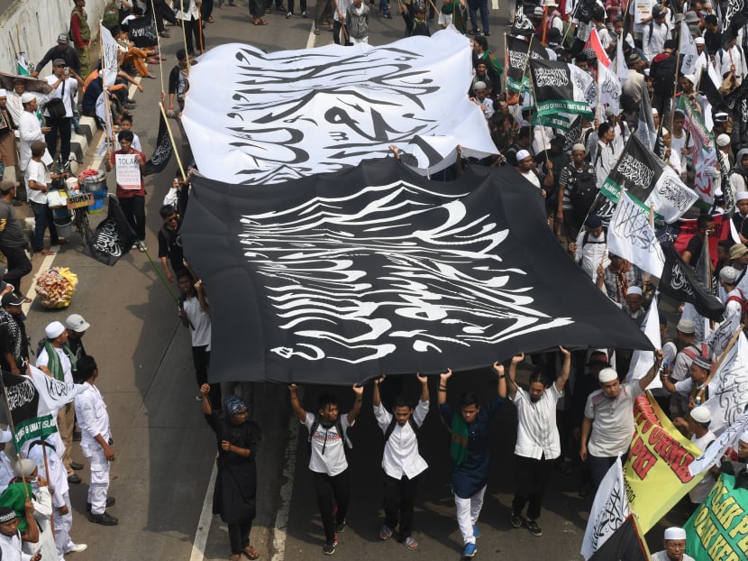 Indonesian Muslims carry flags and banners march toward Parliament to mark the 52nd anniversary of the murder of six army generals and a young lieutenant by rebel armed forces personnel during an abortive coup against then president Sukarno in Jakarta. Photo: AFP