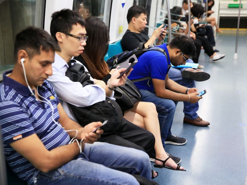 Commuters using their mobile devices inside the cabin of the Circle Line MRT. TODAY file photo