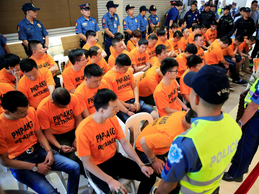 Policemen guard some of the 43 arrested foreigners, mostly Chinese nationals, for kidnapping a Singaporean woman at a casino resort in the capital, during a presentation inside the Philippine National Police (PNP) Headquarters in Quezon City, metro Manila, Philippines July 20, 2017. Photo: Reuters