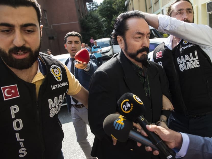 Turkish police officers escort televangelist and leader of a sect, Adnan Oktar (centre) on July 11, 2018, in Istanbul, as he is arrested on fraud charges.