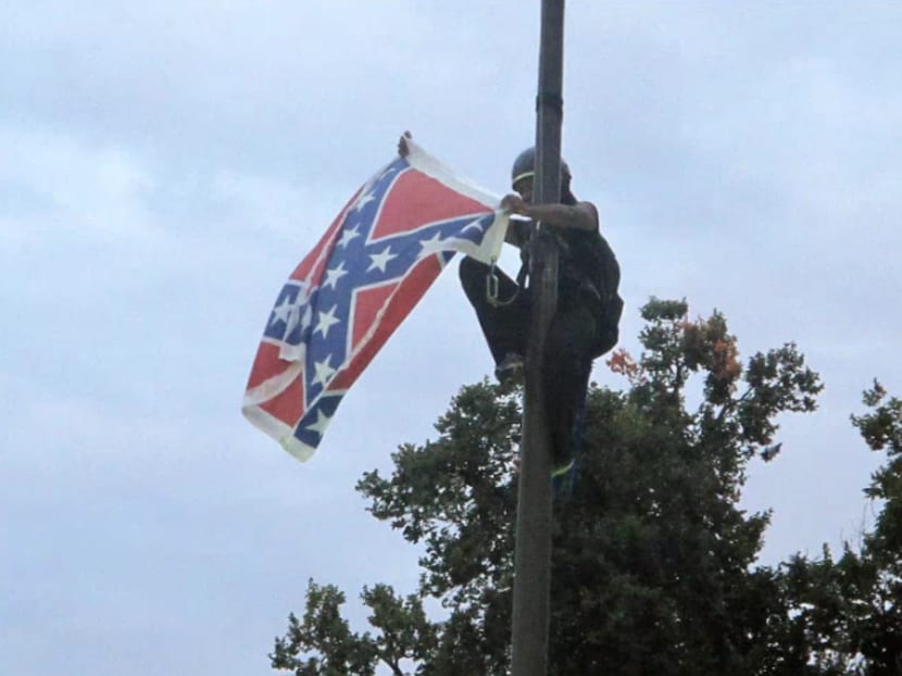 Bree Newsome of Charlotte removes the Confederate battle flag at a Confederate monument at the Statehouse in Columbia, South Carolina, on Saturday, June, 27, 2015. Photo: AP