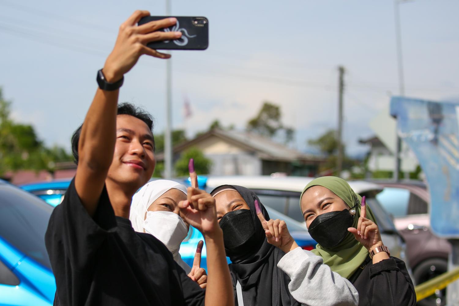 Young voters taking a wefie with their ink-stained index fingers after voting at a polling centre in Satok, Kuching on Nov 19, 2022. 