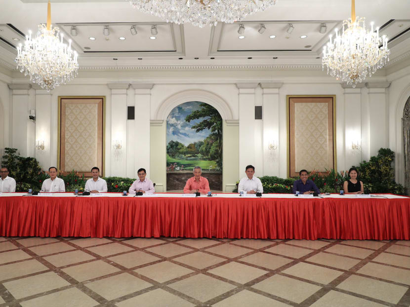 Prime Minister Lee Hsien Loong (fourth from right), flanked by seven political officeholders, during a briefing on July 25, 2020 to unveil the latest Cabinet line-up.