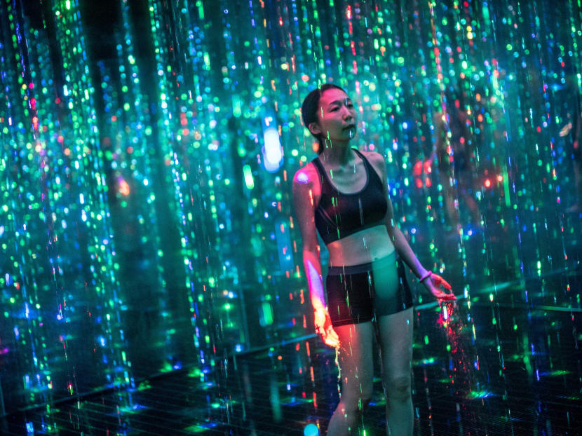 A staff member walks inside an interactive installation "Ephemeral Solidified Light" during a media preview of the "teamLab Reconnect: Art with Rinkan Sauna" art and sauna experience organised by teamLab and Tiktok, in the Roppongi district of Tokyo on March 15, 2021.