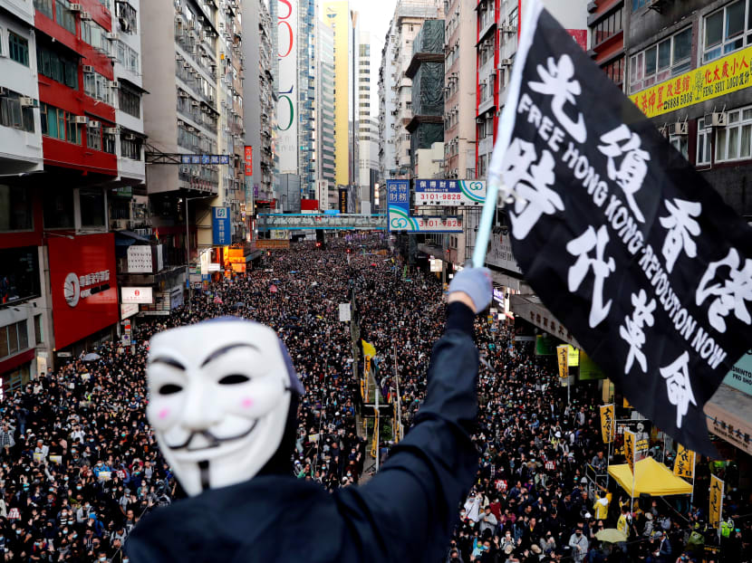 A protester wearing a Guy Fawkes mask waves a flag during a Human Rights Day march organised by the Civil Human Right Front in Hong Kong, Dec 8, 2019.