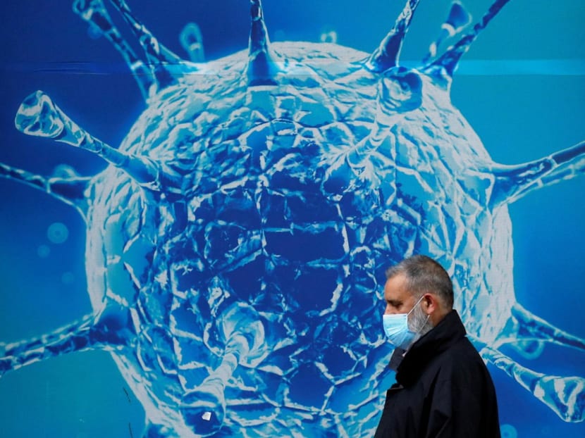 A man wearing a protective face mask walks past an illustration of a virus outside a regional science centre, as the city and surrounding areas face local restrictions in an effort to avoid a local lockdown being forced upon the region, amid the coronavirus disease (Covid-19) outbreak, in Oldham, Britain Aug 3, 2020.