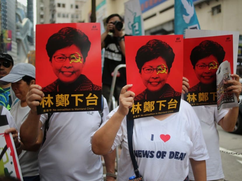 Protesters cover their faces with posters of Hong Kong Chief Executive Carrie Lam during the march from Causeway Bay to the government headquarters in Admiralty.