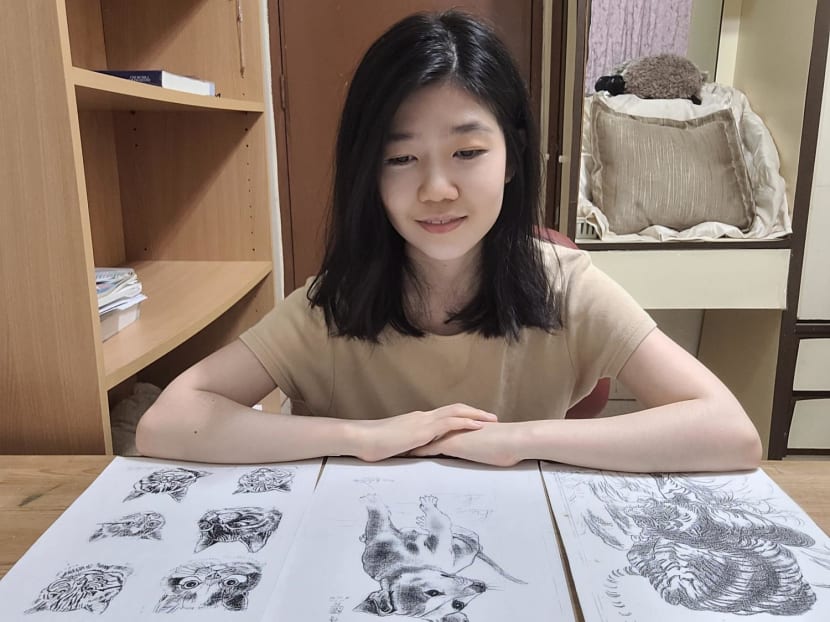 The author is seen here with photocopies of the drawings made by a janitor from her primary school which she has kept. 