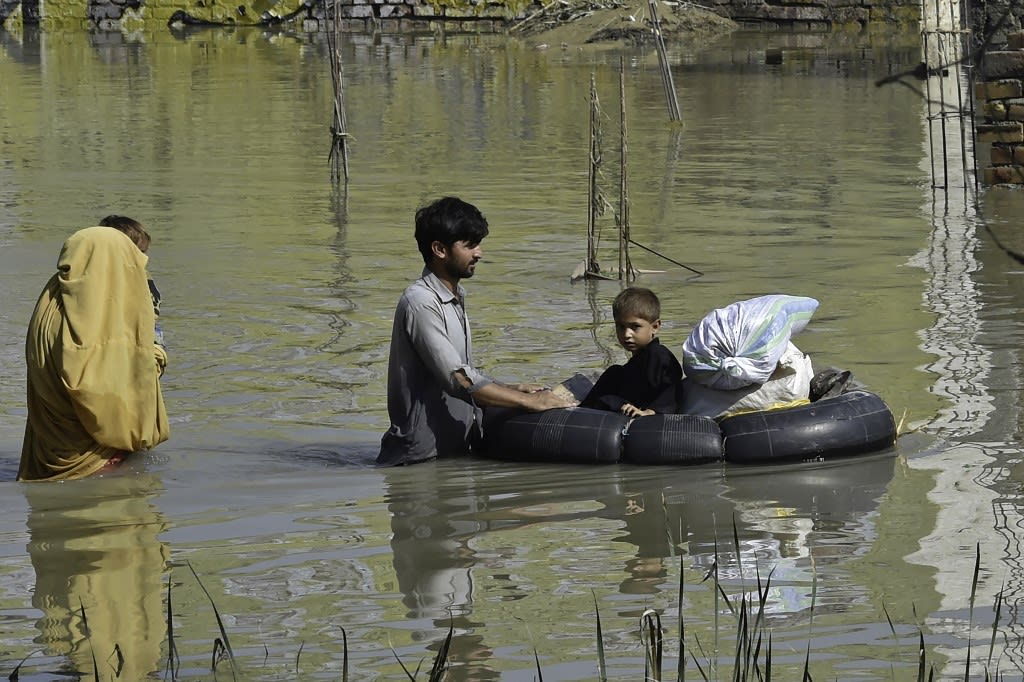 A family wades through a flood hit area following heavy monsoon rains in Charsadda district of Khyber Pakhtunkhwa on Aug 29, 2022.