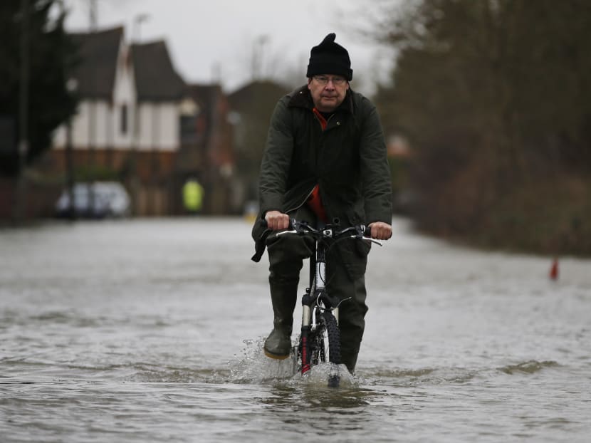 A local resident cycles through the flooded part of the town of Staines-upon-Thames, England, Wednesday, Feb. 12, 2014. Photo: AP